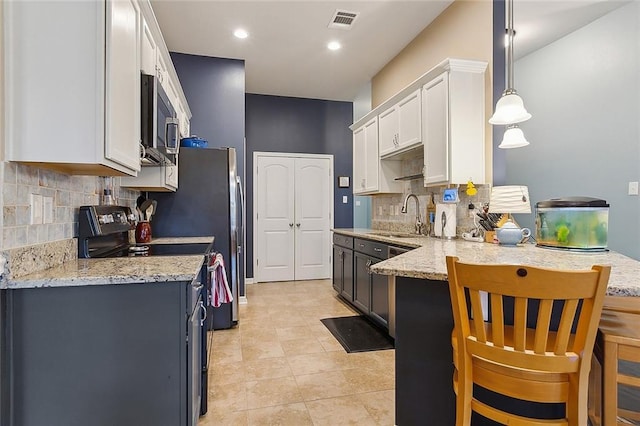 kitchen with visible vents, a peninsula, a sink, white cabinets, and stainless steel microwave