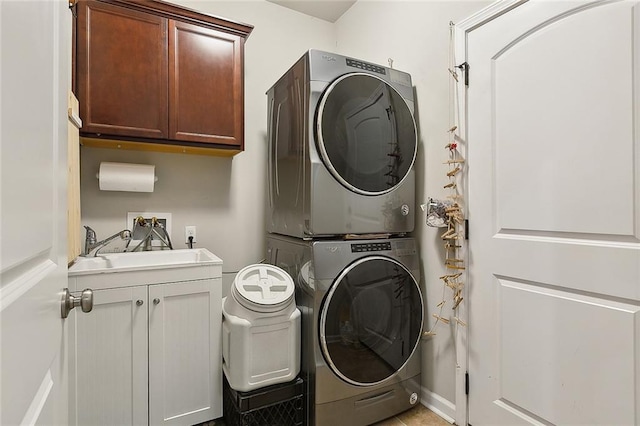 laundry area featuring cabinet space, stacked washing maching and dryer, and a sink