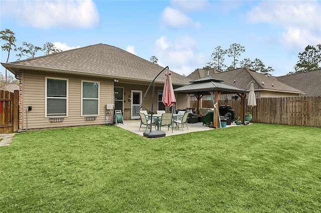 back of house featuring a fenced backyard, a shingled roof, a gazebo, a patio area, and a lawn