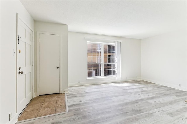 foyer entrance with baseboards, a textured ceiling, and wood finished floors