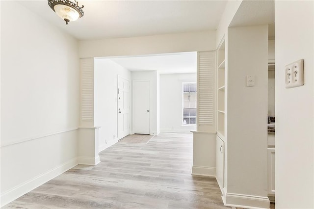 hall with light wood-style flooring and baseboards