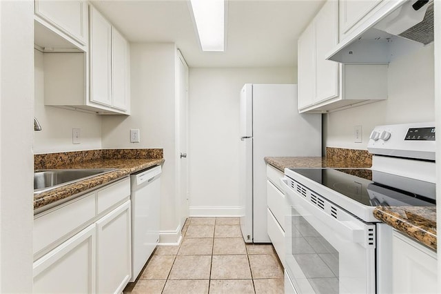 kitchen featuring baseboards, under cabinet range hood, light tile patterned floors, white cabinets, and white appliances