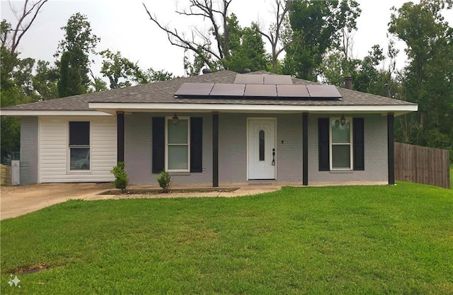 ranch-style home featuring fence, a porch, a front lawn, brick siding, and roof mounted solar panels