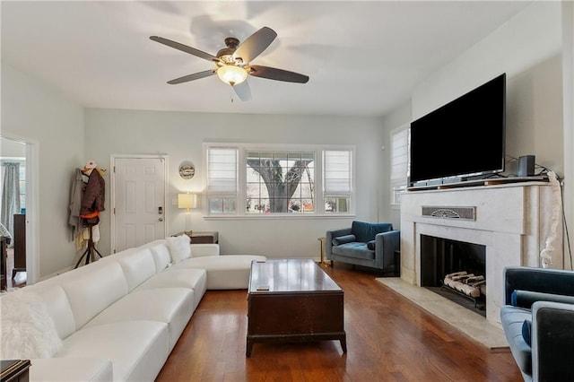 living area with a fireplace with flush hearth, wood finished floors, and a ceiling fan