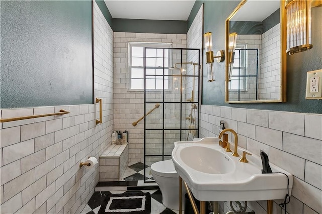 full bathroom featuring toilet, wainscoting, a stall shower, tile walls, and a sink