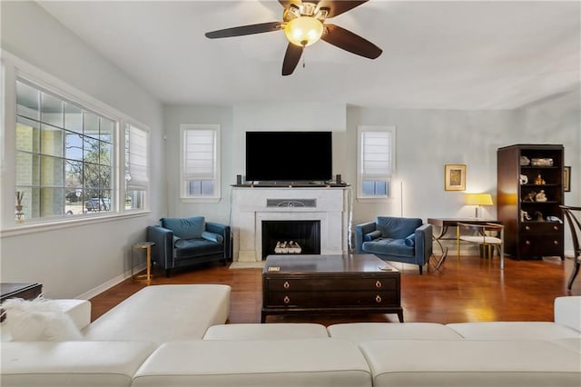 living room with baseboards, a fireplace with flush hearth, wood finished floors, and a ceiling fan