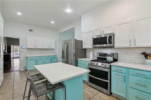 kitchen featuring visible vents, light tile patterned flooring, appliances with stainless steel finishes, a kitchen bar, and blue cabinets