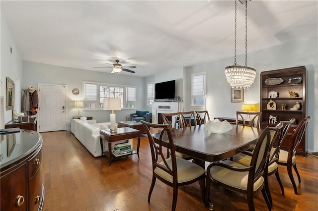 dining area featuring dark wood-style flooring and ceiling fan with notable chandelier