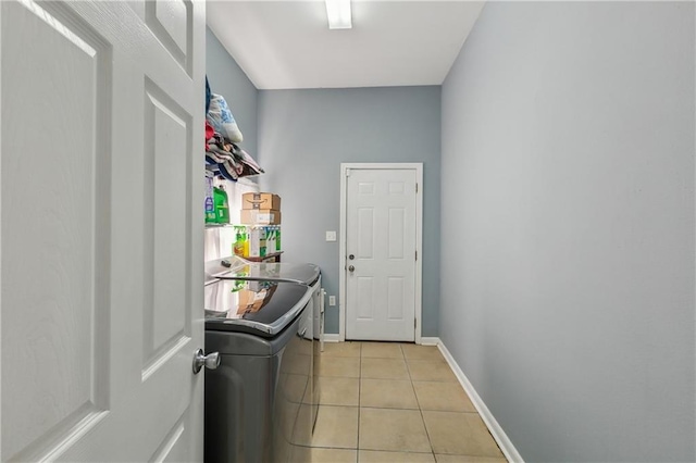 laundry room with baseboards, light tile patterned flooring, laundry area, and washing machine and clothes dryer