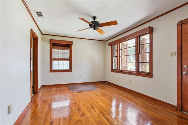 empty room featuring ornamental molding, visible vents, light wood finished floors, and ceiling fan