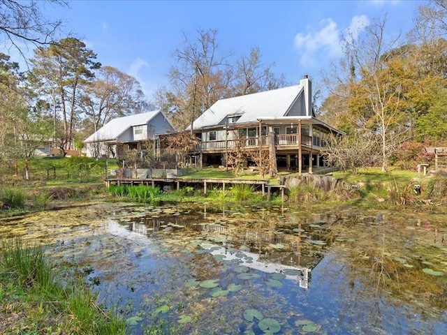 rear view of house featuring a chimney and a deck with water view