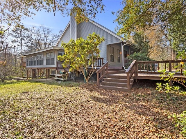 rear view of property with a wooden deck, a chimney, and a sunroom