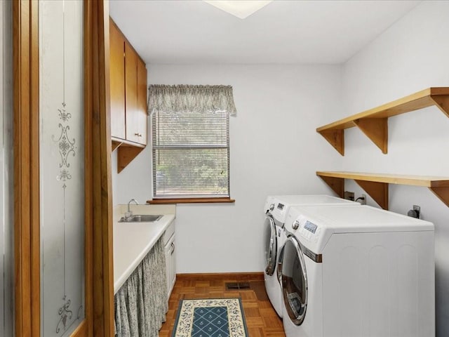 clothes washing area featuring washing machine and dryer, cabinet space, visible vents, and a sink