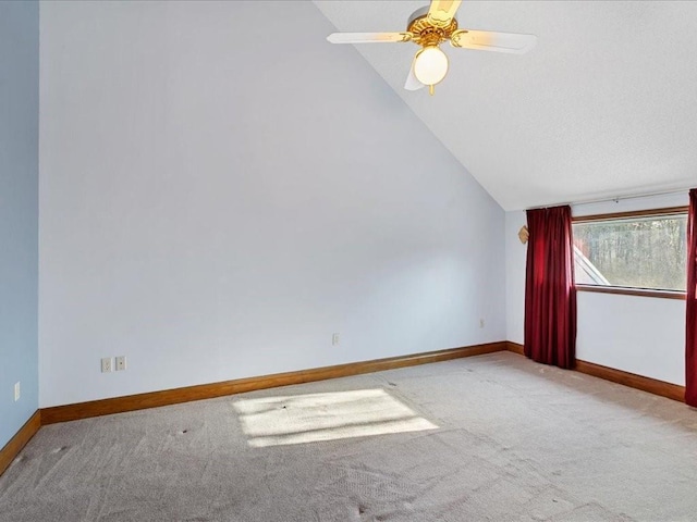 spare room featuring baseboards, carpet floors, ceiling fan, and vaulted ceiling