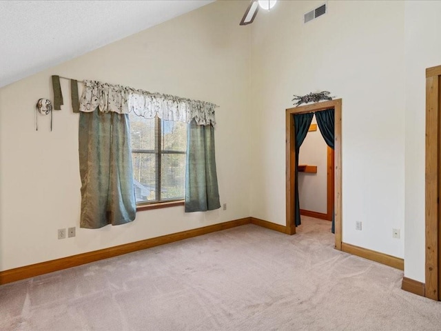 spare room with visible vents, baseboards, carpet, high vaulted ceiling, and a ceiling fan