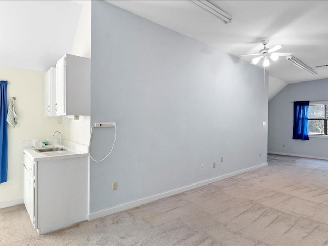 interior space with baseboards, lofted ceiling, a sink, ceiling fan, and light colored carpet