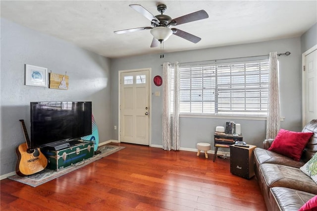 living area with a ceiling fan, wood-type flooring, and baseboards