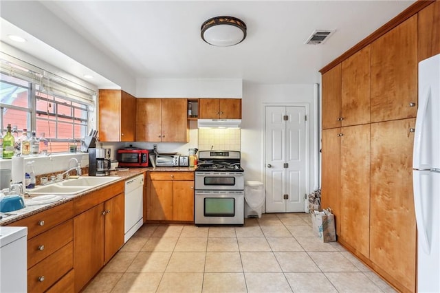 kitchen featuring white appliances, brown cabinets, decorative backsplash, and a sink