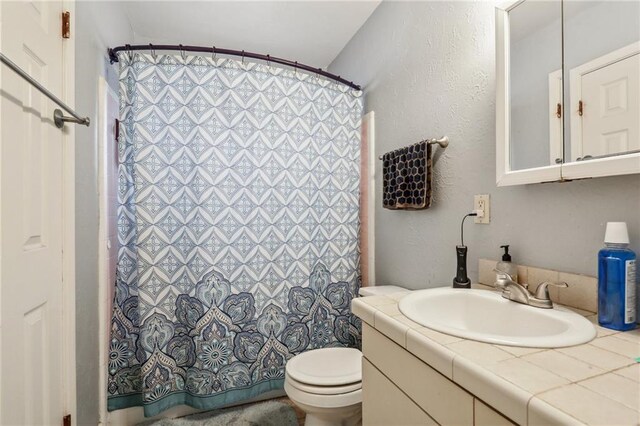 bathroom with toilet, a shower with shower curtain, and vanity