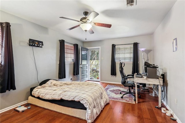 bedroom featuring wood finished floors, an office area, baseboards, and a ceiling fan