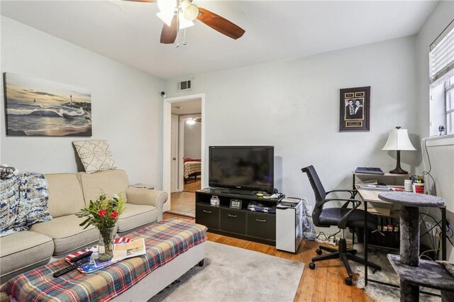 living area with a ceiling fan, an office area, and wood finished floors