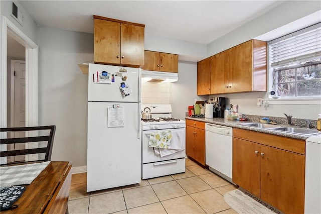 kitchen with white appliances, under cabinet range hood, a sink, light tile patterned floors, and brown cabinetry