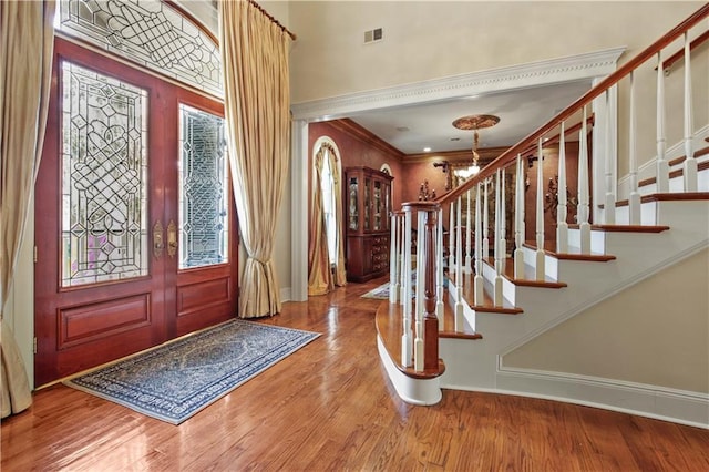 entrance foyer featuring crown molding, baseboards, stairway, an inviting chandelier, and wood finished floors