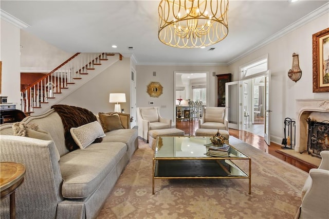 living area featuring stairs, crown molding, a notable chandelier, and wood finished floors