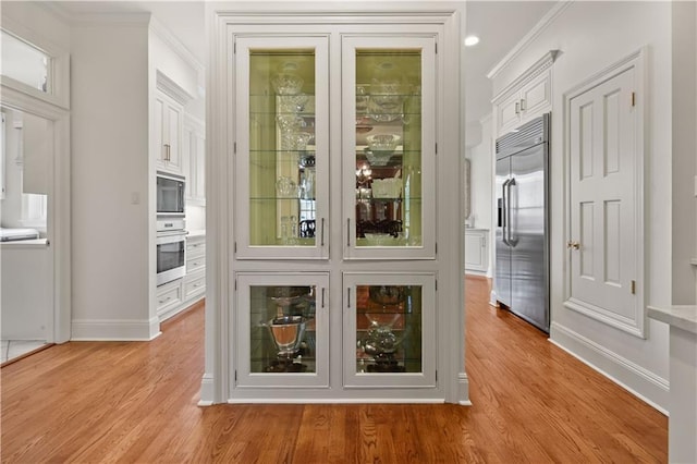 interior space with light wood-type flooring, baseboards, and ornamental molding