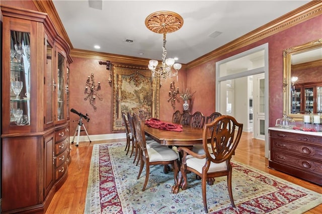 dining area with visible vents, crown molding, light wood finished floors, baseboards, and a chandelier