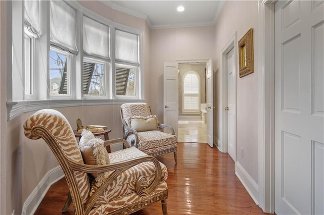 sitting room featuring baseboards, a healthy amount of sunlight, wood finished floors, and crown molding