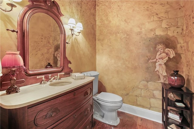 bathroom with vanity, toilet, wood finished floors, and baseboards