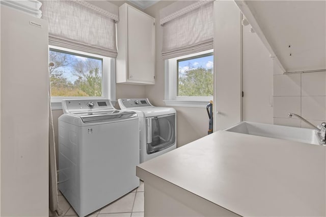 laundry area with a sink, cabinet space, washing machine and dryer, and light tile patterned flooring