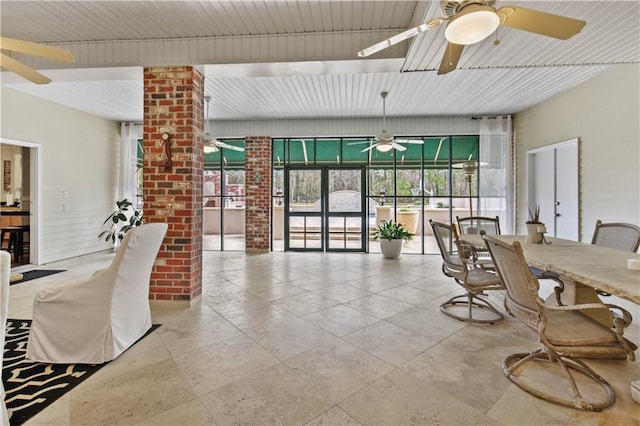 dining area featuring ceiling fan and brick wall