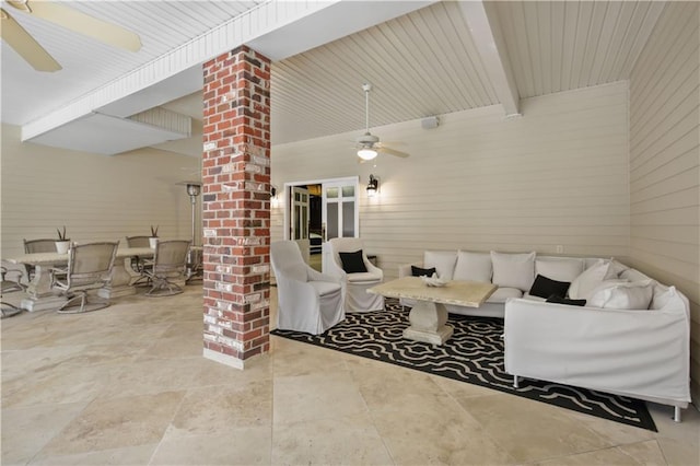 living area with beamed ceiling, a ceiling fan, and ornate columns