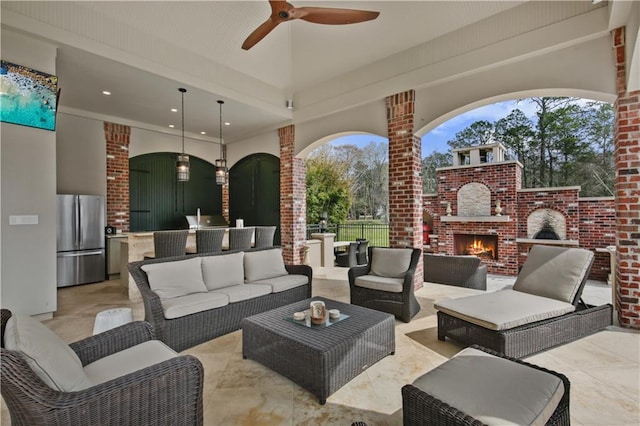 view of patio / terrace with an outdoor living space with a fireplace, exterior kitchen, a ceiling fan, and fence