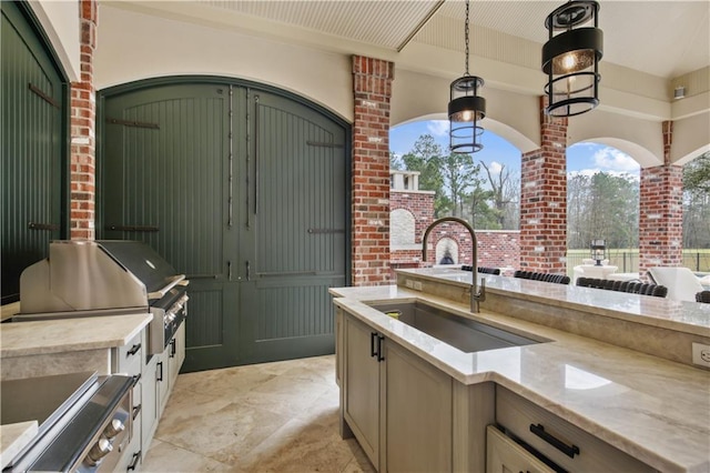 kitchen featuring a sink, light stone counters, and pendant lighting