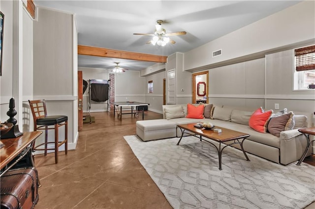 living area with a decorative wall, a ceiling fan, visible vents, and concrete floors