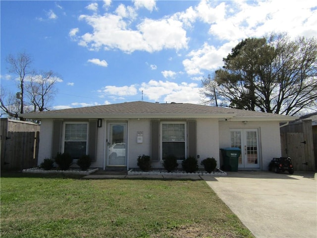 ranch-style home featuring fence, french doors, roof with shingles, a front yard, and brick siding