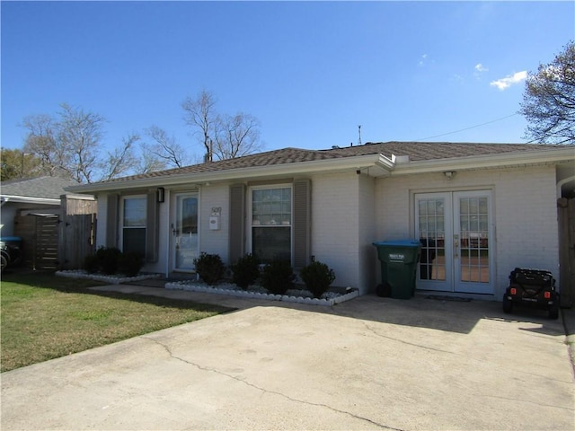 ranch-style home with a front lawn, fence, french doors, and brick siding