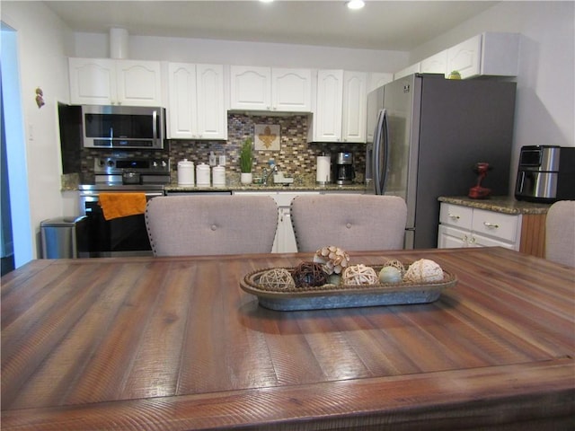 kitchen featuring decorative backsplash, appliances with stainless steel finishes, wood counters, and white cabinetry