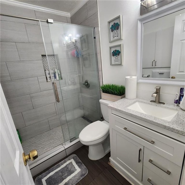 full bath featuring crown molding, toilet, a stall shower, wood finished floors, and vanity