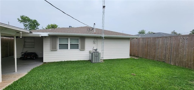 rear view of house featuring a yard, fence, and central AC