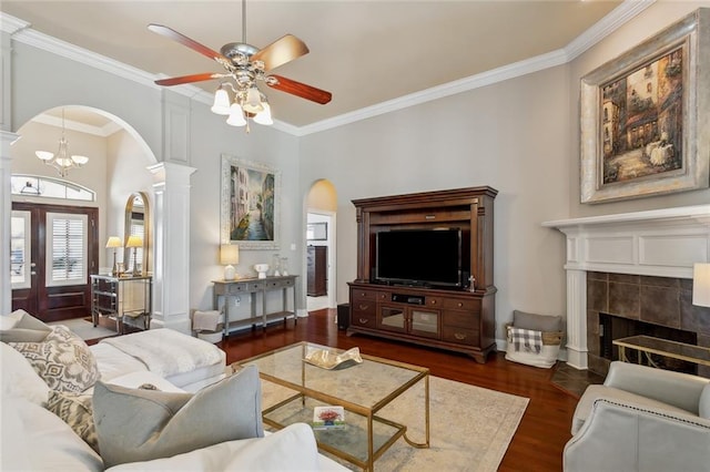 living area featuring wood finished floors, arched walkways, ceiling fan, and ornate columns