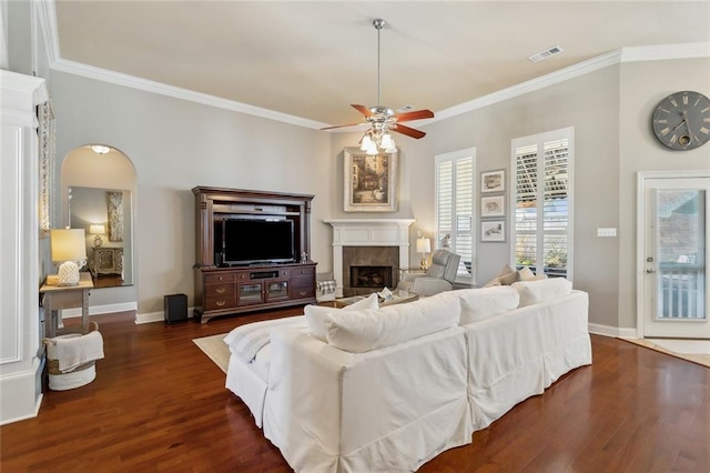 living room featuring a tiled fireplace, visible vents, dark wood-type flooring, and a ceiling fan