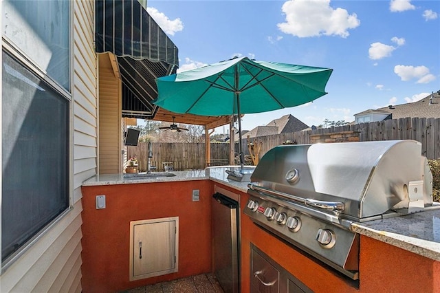 view of patio with a sink, a grill, a fenced backyard, and exterior kitchen