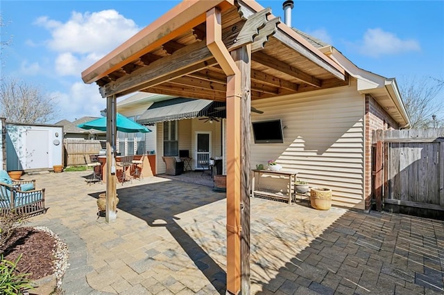 view of patio / terrace with outdoor dining space, a gate, fence, a shed, and an outdoor structure