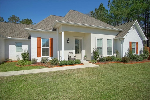 view of front facade featuring stucco siding, roof with shingles, and a front lawn