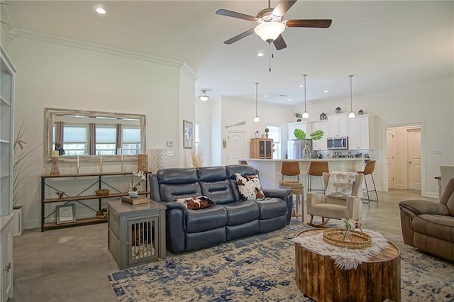 living area with baseboards, ornamental molding, and a ceiling fan