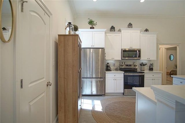 kitchen with appliances with stainless steel finishes, white cabinetry, light countertops, and ornamental molding